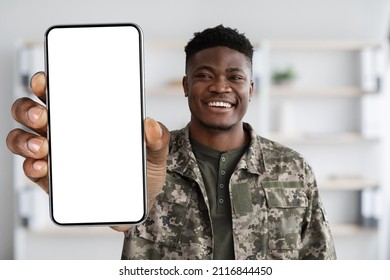 Attractive black soldier in military uniform showing his smartphone with white empty screen and smiling, recommending mobile application for psychological support for military personnel, mockup - Powered by Shutterstock