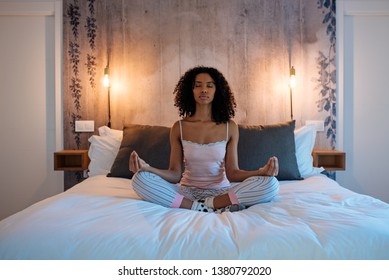 Attractive Black Woman Sitting In Lotus Position On Bed Meditating