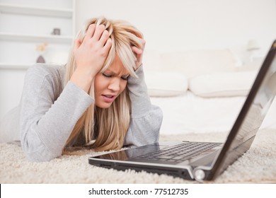 Attractive Blond Woman Angry With Her Computer Lying On A Carpet In The Living Room