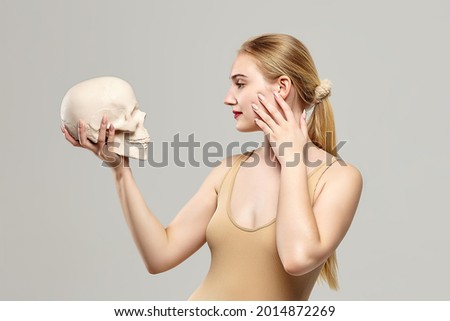 attractive blonde holds a skull in her hands. the concept of photography is suitable in the field of cosmology, medicine and healthcare.