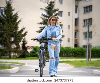 Attractive blonde in jeans pushing electric bicycle posing for the shot  - Powered by Shutterstock