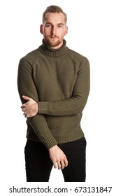 Attractive Blonde Man Standing Against A White Background Wearing A Green Turtle Neck Shirt Looking At Camera.