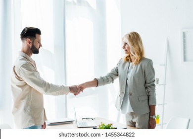attractive blonde recruiter and handsome employee shaking hands 
