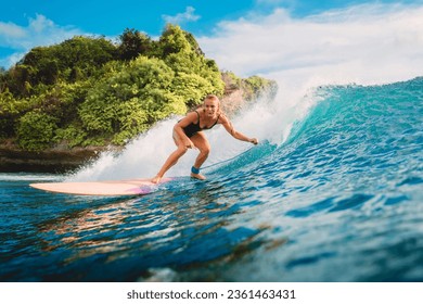 Attractive blonde surf girl riding on surfboard in ocean. Surfer on blue wave during surfing - Powered by Shutterstock