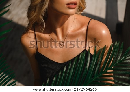 Attractive blonde woman in a black silk tank top and neck jewelry