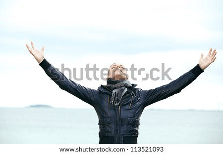 Attractive blonde woman standing rejoicing with her arms outspread and her head tilted back looking at the skies