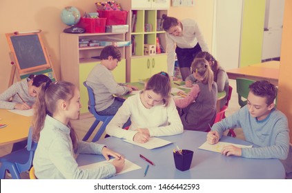 attractive boy and girl holding thumbs up, standing in class with kids