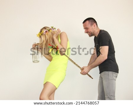 attractive boy whipping young girl with homemade easter whip on easter monday. tradition in slovakia and Czechrepublic. man and woman having fun. lady holding bottle of alcohol. flower wreath on head