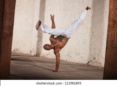 Attractive Brazilian man performing a capoeria kick