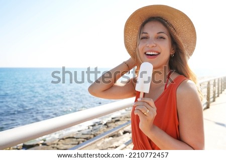 Attractive Brazilian woman eating a lemon popsicle looking at the camera on summer