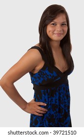Attractive brunette aboriginal teen smiling showing dimple with long hair wearing blue dress standing over white