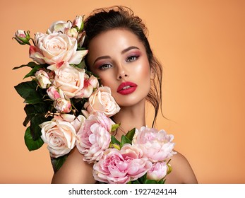Attractive brunette girl with big beautiful  bouquet of  flowers. Beautiful white girl with flowers.  Pretty woman with bright makeup. Art portrait with flowers.