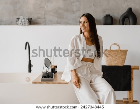 attractive brunette smiling woman dressed in boho white clothes stylish relaxing in bathroom spa, long black hair