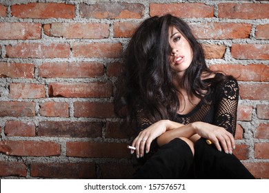 Attractive Brunette Smoking On Wall Background