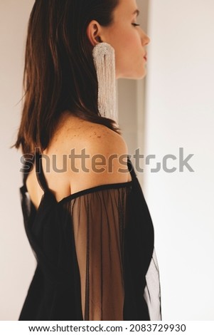 Attractive brunette woman wear black cotton and guipure cocktail dress featuring long lantern sleeves, open back. Model wearing evening outfit. Dress with cut back. Look from back. Focus on sleeve.
