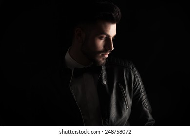 Attractive business man looking down to his side on dark studio background.