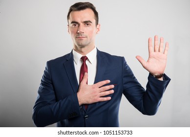 Attraktiver Geschäftsmann, der eine Eid-Geste auf grauem Hintergrund aussieht