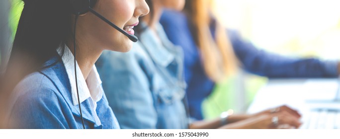 Attractive business woman Asian in suits and headsets are smiling while working with computer at office. Customer service assistant working in office