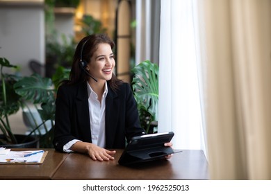 Attractive Business Woman Asian In Suits And Headsets Are Smiling While Working With Computer At Office. Customer Service Assistant Working In Office. VOIP Helpdesk Headset