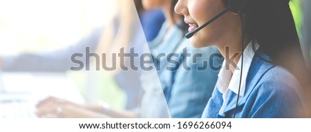 Attractive business woman Asian in suits and headsets are smiling while working with computer at office. Customer service assistant working in office. panorama and panoramic banner design