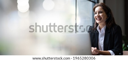 Attractive business woman Asian in suits and headsets are smiling while working with computer at office. Customer service assistant working in office. VOIP Helpdesk headset. panorama banner background