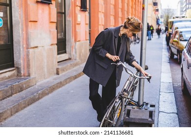 Attractive Business Woman Come To Sits On Bike. Girl Wear Grey Jacket Or Blazer, Black Pants, Eyeglasses. Modern Business Woman Ride To Work On Vehicle. Riding Bicycle To Work. Focus On Bike.