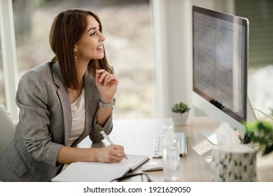 An attractive business woman sitting alone in her home office and working on computer.