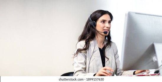 Attractive Business Woman In Suits And Headsets Are Smiling While Working With Computer At Office. Customer Service Assistant Working In One Stop Service Office