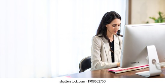 Attractive Business Woman In Suits And Headsets Are Smiling While Working With Computer At Office. Customer Service Assistant Working In One Stop Service Office