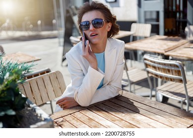 Attractive Business Woman In White Suit Sitting In Cafe And Talking Phone