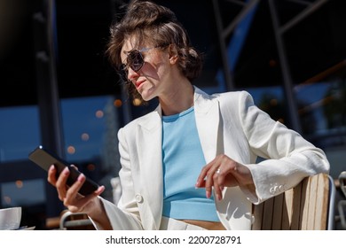 Attractive Business Woman In White Suit Sitting In Cafe And Using Phone