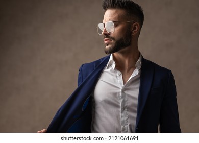 Attractive Businessman Looking To The Side, Pulling His Jacket And Posing With Cool Attitude