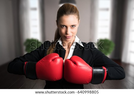 attractive businesswoman with boxing gloves ready for a fight in front of an apartment