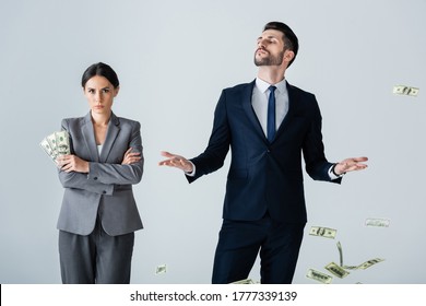 Attractive Businesswoman Holding Dollars Near Arrogant Businessman Standing On White