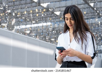 Attractive businesswoman on mobile phone Arab or middle eastern sending and texting. Woman wearing business corporate formal clothes outdoors in Dubai