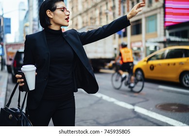 Attractive businesswoman with red lips raising had to call yellow cab on New york avenue, confident trendy dressed female manager hailing on road catching taxi holding coffee to go getting to work
 - Powered by Shutterstock