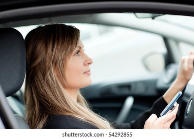 Attractive Businesswoman Sending A Text While Driving To Work