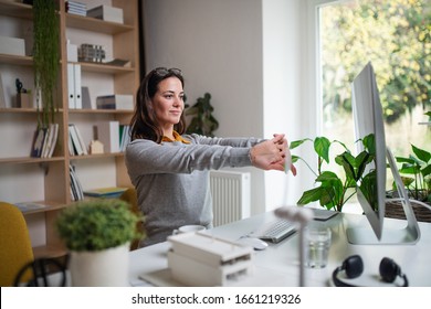 Attractive businesswoman sitting indoors in office, stretching. - Powered by Shutterstock