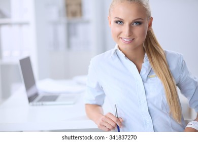 Attraktive Geschäftsfrau, die auf einem Schreibtisch mit Laptop im Internet sitzt