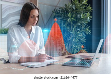 Attractive businesswoman in white shirt at workplace working with laptop to optimize trading strategy at corporate finance fund. Forex chart hologram over office background