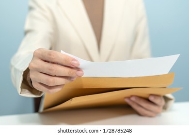 Attractive Businesswoman In White Suit Hand Open Business Report From Document Envelope And Working On Desk In Meeting Room At Home Office, Digital Online Marketing And Financial Business Concept