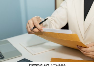 Attractive Businesswoman In White Suit Hand Open Business Report From Document Envelope And Working On Desk In Meeting Room At Home Office, Digital Online Marketing And Financial Business Concept