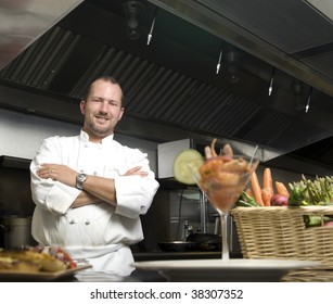 Attractive Caucasian chef standing with arms crossed in a restaurant kitchen.