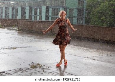 Attractive caucasian female dancing under the summer rain and enjoying with water drops