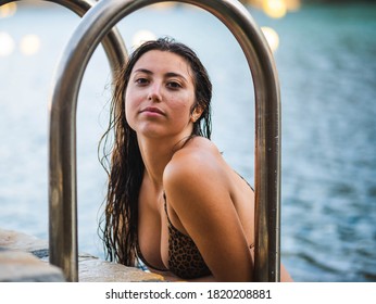 attractive Caucasian female getting out of swimming pool. Woman enjoying swimming in a pool. Woman in swimsuit having fun at the beach - Powered by Shutterstock