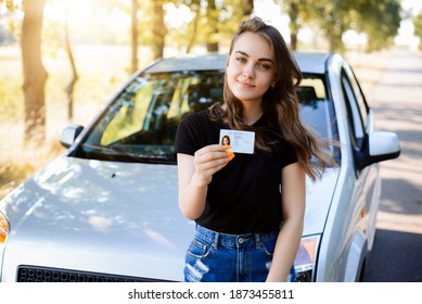 Attractive caucasian girl driver showing her driving license, happy to finish driving school and pass driving examination successfully - Shutterstock ID 1873455811