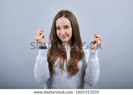 Attractive caucasian lady keeping fingers together, smiling wearing fashion blue sweater isolated on gray background in studio. People emotions, lifestyle concept.