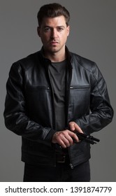 Attractive Caucasian Male With Brown Hair – Action Hero Wearing Leather Jacket And Jeans, Holding Gun