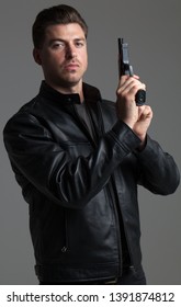 Attractive Caucasian Male With Brown Hair – Action Hero Wearing Leather Jacket And Jeans, Holding Gun