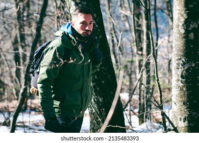 Attractive Caucasian Male Hiking In Forest. Young Hiker Going  Through The Mountain Woods In Late Winter. 